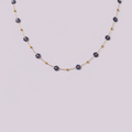 Collier en acier inoxydable doré avec fleurs bleues sur fond lilas