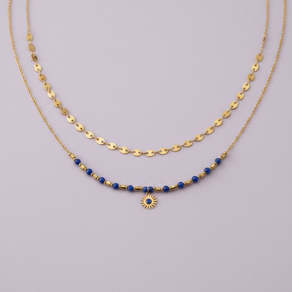 Collier double rang doré avec perles bleues et pendentif soleil sur fond lilas