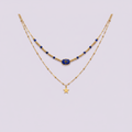 Collier double rang doré avec perles lapis-lazuli et pendentif étoile sur fond lilas